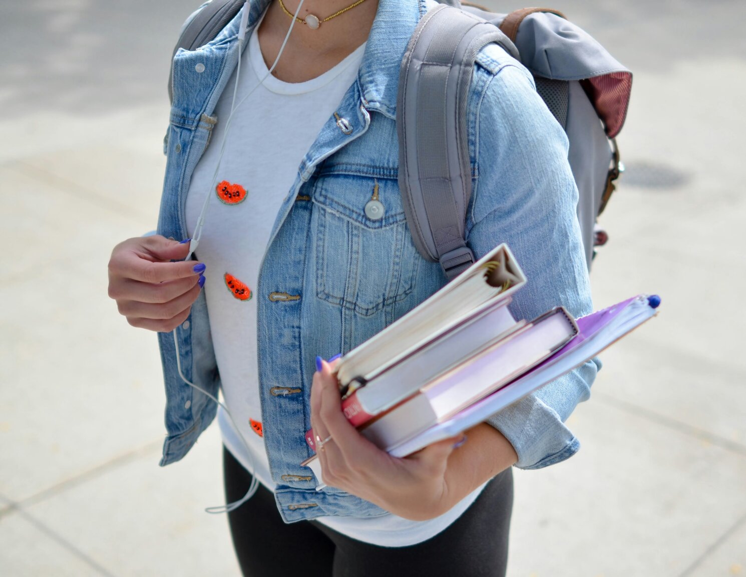 Eine Schülerin in einer Jeansjacke hält mehrere Schulbücher in der Hand